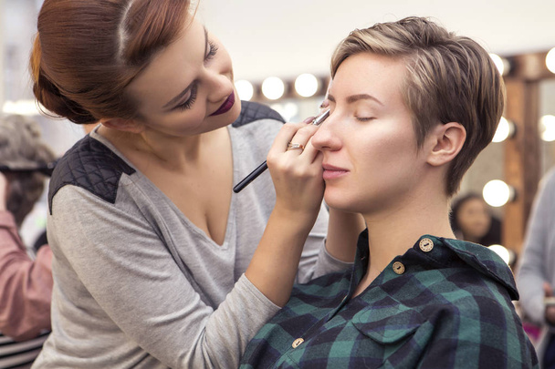 Prachtige brunette vrouw make-up artiest toepassen make up een beroe - Foto, afbeelding