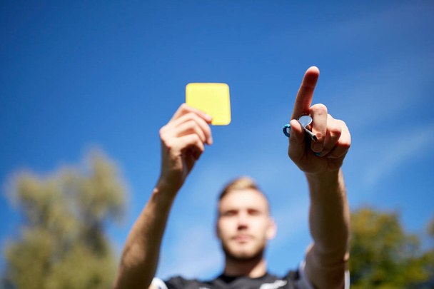 referee on football field showing yellow card - Фото, зображення