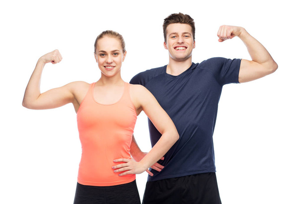 happy sportive man and woman showing biceps power - Photo, Image