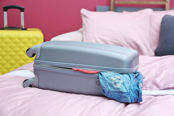 Packed travel suitcase on bed - 写真・画像