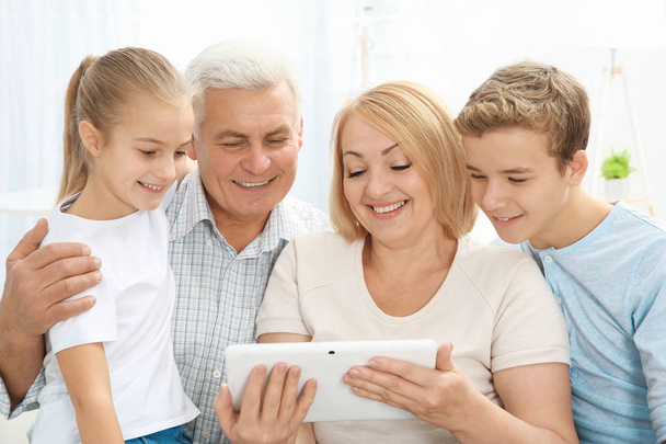 Aranyos gyerekek és a nagyszülők, a nappaliban tabletta számítógép - Fotó, kép