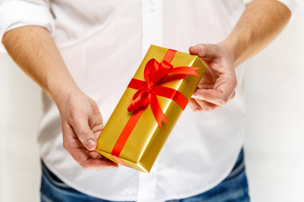 Male hands holding a gift box with ribbon. - Фото, зображення