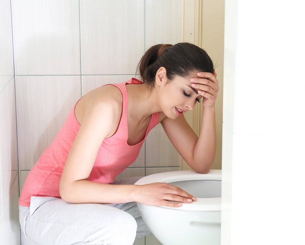 Jeune femme vomissant près du bol de toilette à la maison
 - Photo, image