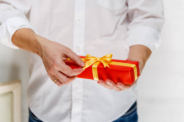 Male hands holding a red gift box with ribbon. - Φωτογραφία, εικόνα
