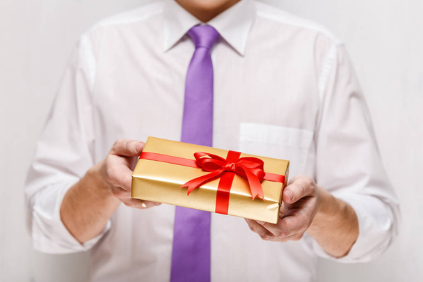 Male hands holding a gift box with ribbon. - Valokuva, kuva