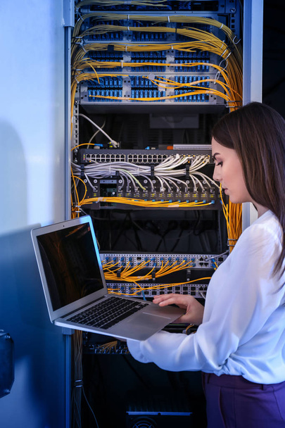 Beautiful young engineer with laptop in server room - Foto, immagini