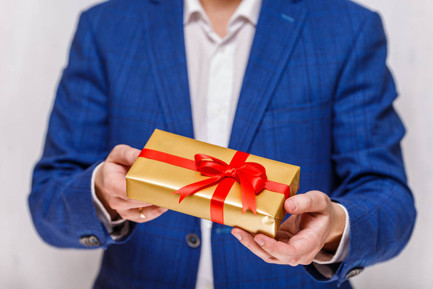 Male hands holding a gift box with ribbon. - 写真・画像