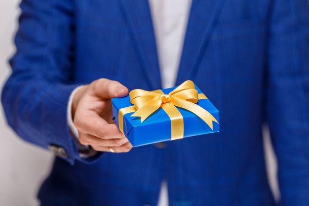 Mano maschile in possesso di una scatola regalo blu con nastro
. - Foto, immagini