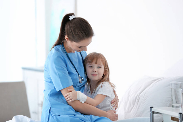 Doctor embracing little girl in hospital room - Fotoğraf, Görsel