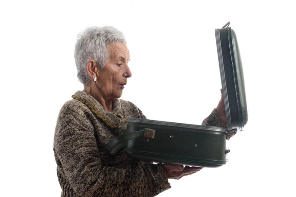 Удивлённая пожилая женщина открывает винтажный чемодан
 - Фото, изображение