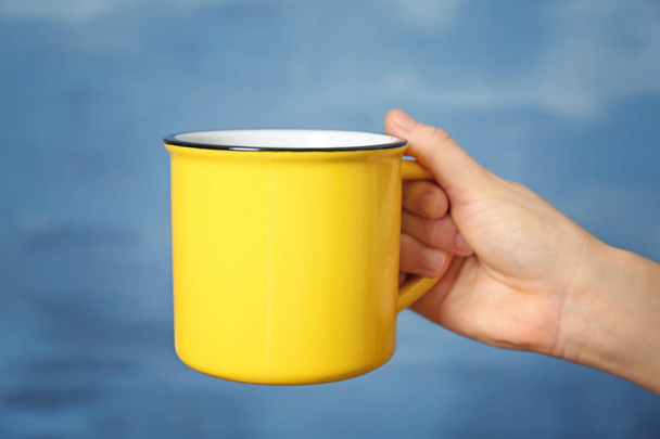 Blank yellow cup in hand - Foto, Imagen