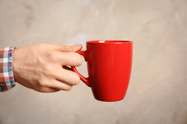 Male hand holding red cup - Foto, imagen