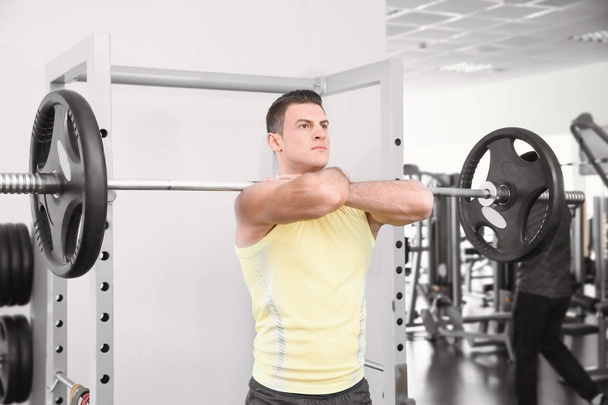 Young handsome man with barbell training in gym - Photo, image