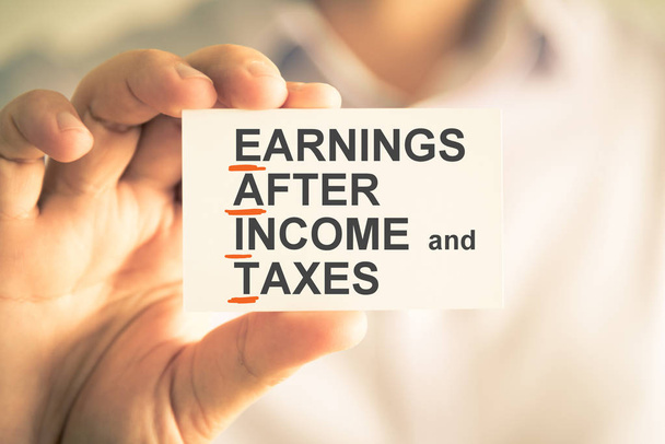 Geschäftsmann hält Karte mit Eait Ergebnis nach Einkommen und Steuern Akronym Text - Foto, Bild