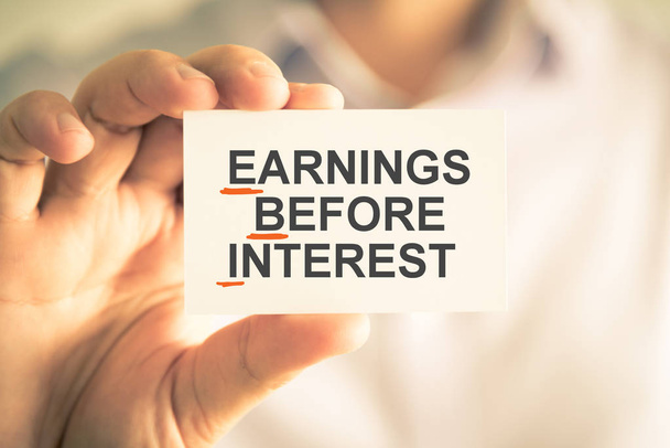 Businessman holding card with EBI EARNINGS BEFORE INTEREST acronym text - Photo, Image