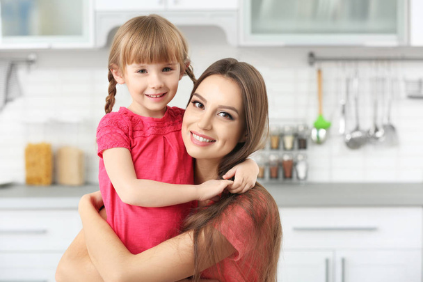 Young mother embracing little girl at kitchen - Foto, imagen