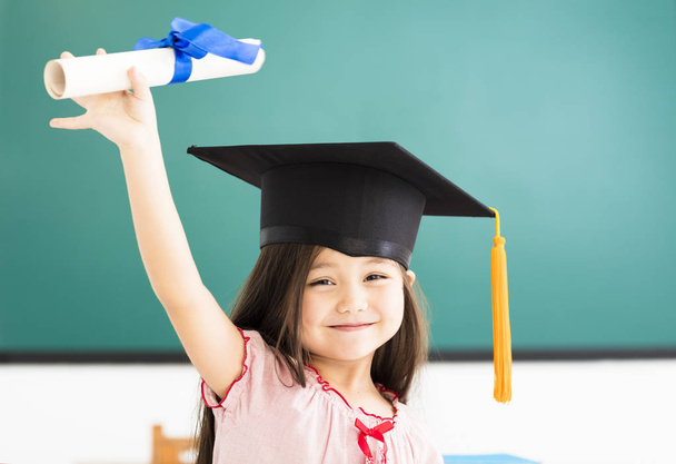 Πορτρέτο του χαριτωμένο μαθήτρια με καπέλο αποφοίτησης στην τάξη - Φωτογραφία, εικόνα