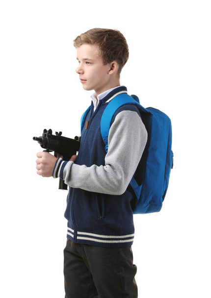 Teenage boy with backpack holding gun on white background - Foto, imagen