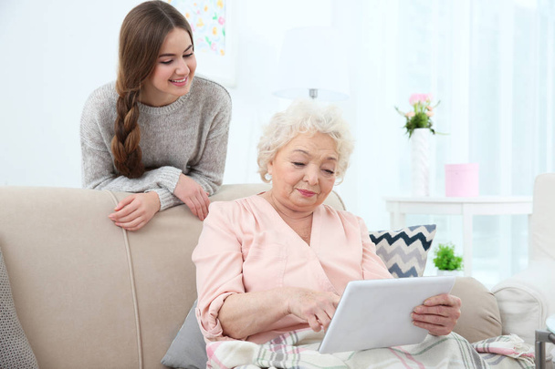 Beautiful girl with grandmother using tablet at home - Foto, Imagem