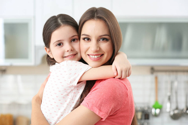 Young mother embracing little girl at kitchen - Photo, image