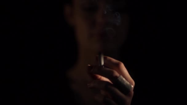 Woman smoking a cigarette coming out of the dark - Video