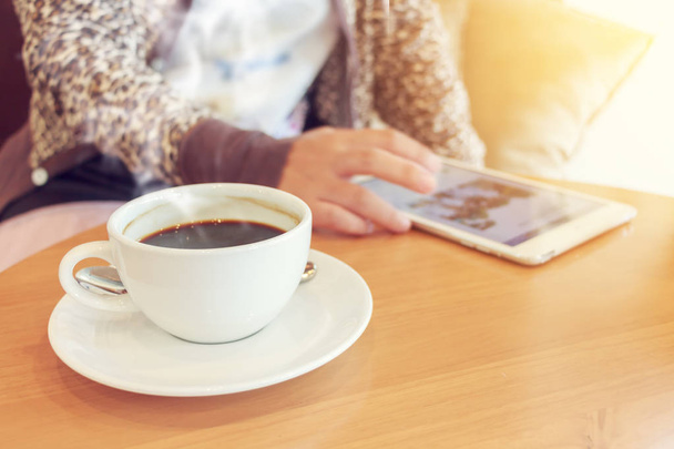 Woman using tablet computer and drinking coffee.  - Photo, Image