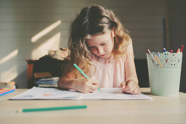 child girl drawing at home with colored pencils - Foto, afbeelding