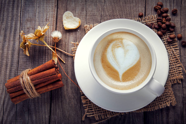 xícara de café cappuccino na velha mesa de madeira vintage, flor seca
 - Foto, Imagem