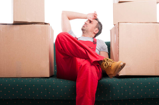 Homme de déménagement fatigué assis sur le canapé avec des boîtes en carton autour
 - Photo, image