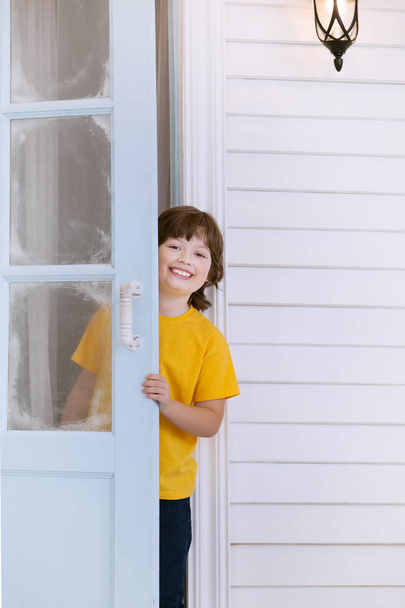 child opens the door of a house in the village - Φωτογραφία, εικόνα
