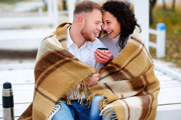 Jovem casal abraçando e coberto com um cobertor quente sentado o
 - Foto, Imagem
