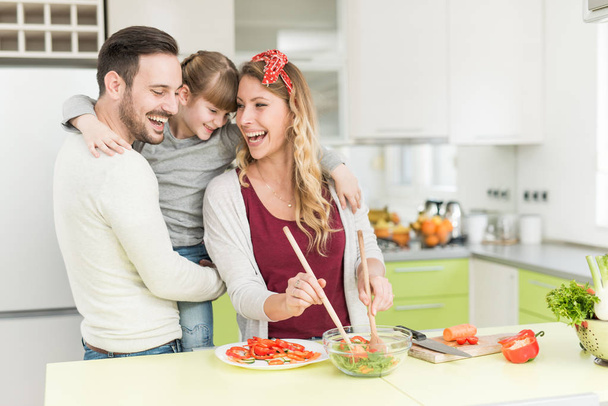 Boldog fiatal család, ebéd készül a konyhában  - Fotó, kép