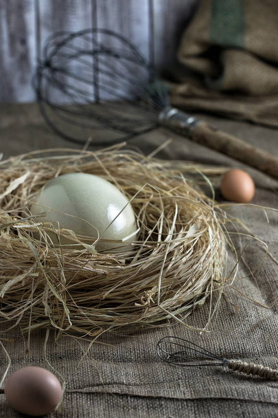Struisvogel eieren in het nest, grote en kleine eggbeaters op sackloth backgr - Foto, afbeelding