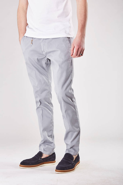 Man is standing  in light studio in trendy light grey chinos and black shoes - Foto, imagen