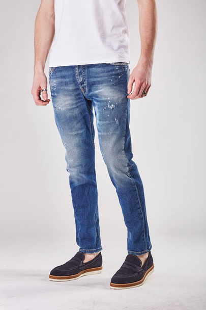 Man is posing in light studio in trendy blue denim jeans pants and black shoes - Photo, Image