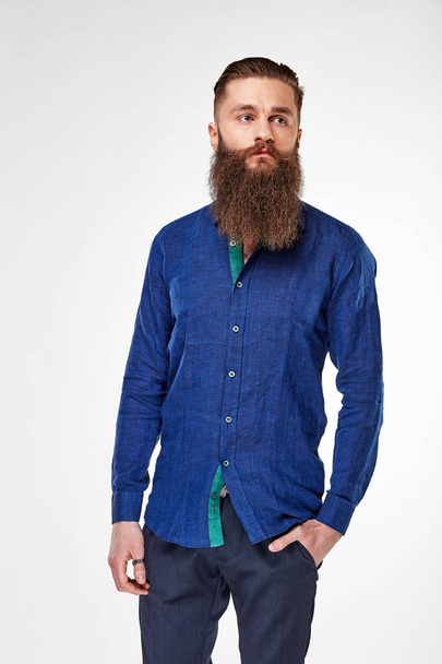 Young bearded man posing in studio in trendy linen deep blue shirt and blue pants - Fotoğraf, Görsel