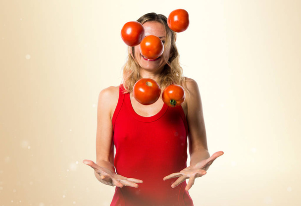Mulher loira bonita segurando tomates no fundo ocre
 - Foto, Imagem