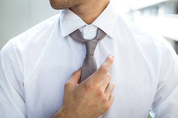 Businessman touching the neck tie - Zdjęcie, obraz