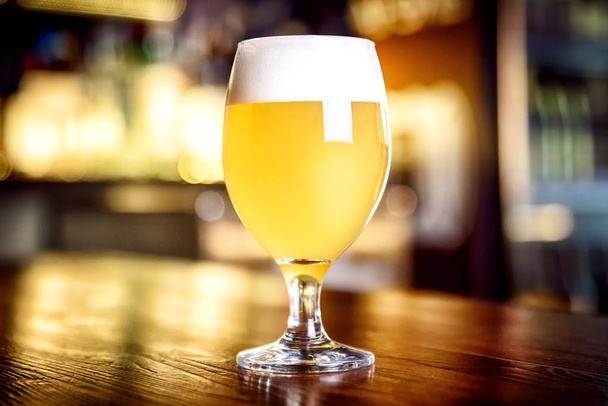 Glass of light beer on a pub with bokeh background - 写真・画像