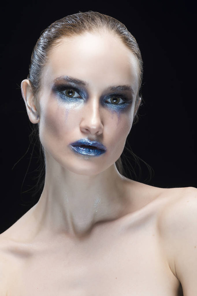 portrait of the young woman with blue lips and vanguard shine blue make-up isolated on a black background - Photo, image