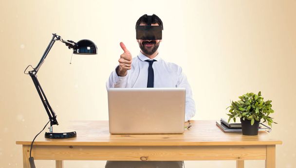Geschäftsmann in seinem Büro mit VR-Brille mit erhobenem Daumen - Foto, Bild