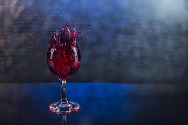 Splash in red juice or wine in a wineglass - Foto, afbeelding
