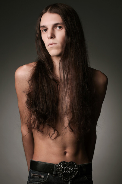 Portrait of a handsome long haired brunet male model over gray b - Photo, Image