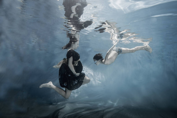 Femme enceinte posant avec son aîné posant sous l'eau
 - Photo, image