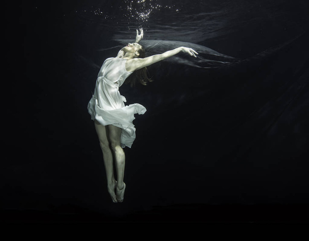 Nuori ballerina tanssii veden alla.
 - Valokuva, kuva