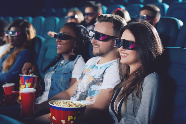 Vrienden kijken naar film in de bioscoop en lachend samen. - Foto, afbeelding