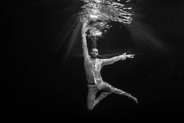 Nuori balettitanssija poseeraa veden alla.
 - Valokuva, kuva