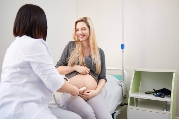 Pregnant woman having ultrasonic scanning at the clinic - Foto, Bild