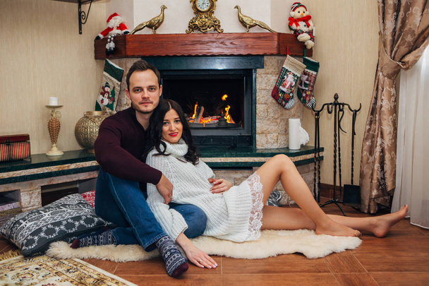 happy beautiful couple in love near fireplace posing at the camera - Foto, afbeelding