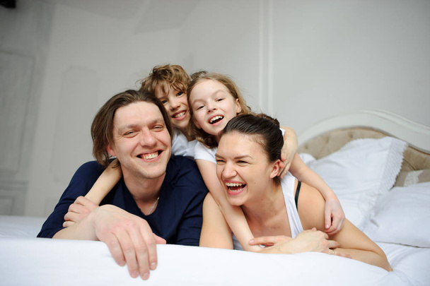 Giovani genitori e il loro figlio e figlia giocano in camera da letto
 - Foto, immagini